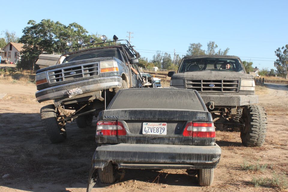 1992 Ford Bronco front view, lifted with off-road tires, next to another lifted truck and a Volvo