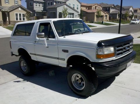 1995 Ford Bronco - A white 1995 Ford Bronco is parked on a suburban driveway.