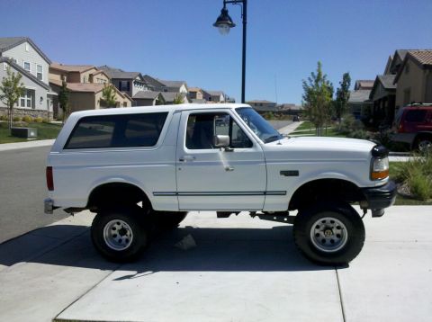 1995 Ford Bronco - This lifted 1995 Ford Bronco is shown from the side, aftermarket wheels and a clean white exterior.