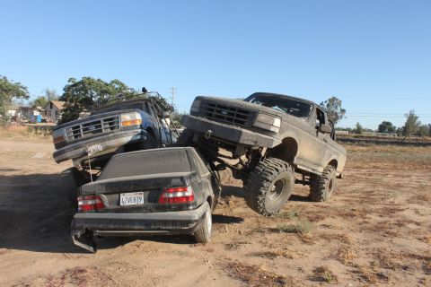 Lifted 1992 Ford Bronco crushing a black sedan