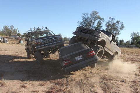 1992 Ford Bronco crushing a sedan on a dirt trail