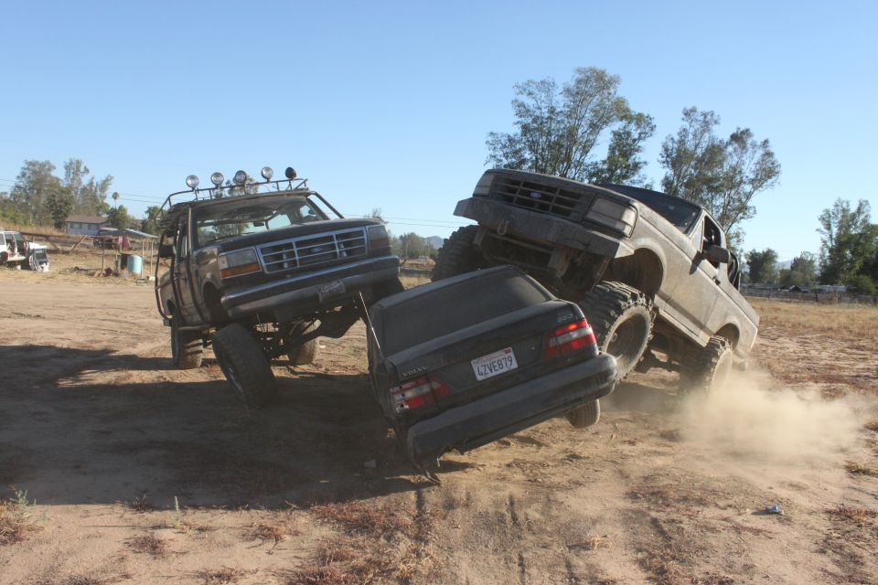 1992 Ford Bronco crushing a sedan on a dirt trail