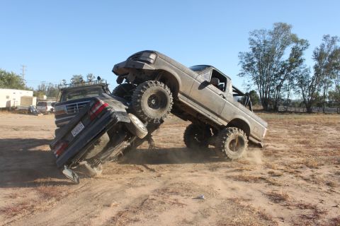 Two lifted trucks engaged in a car crush event