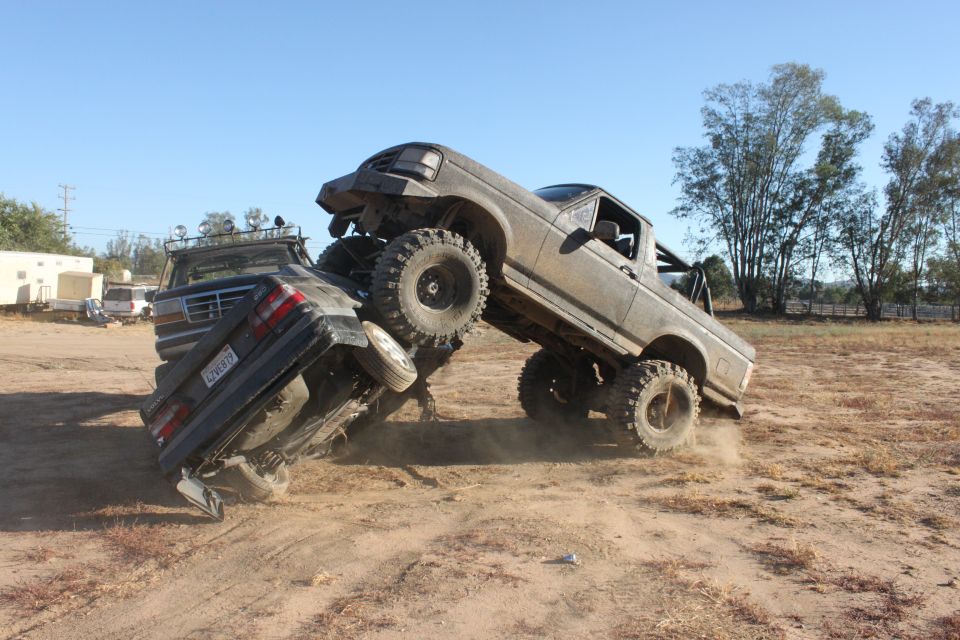 Two lifted trucks engaged in a car crush event