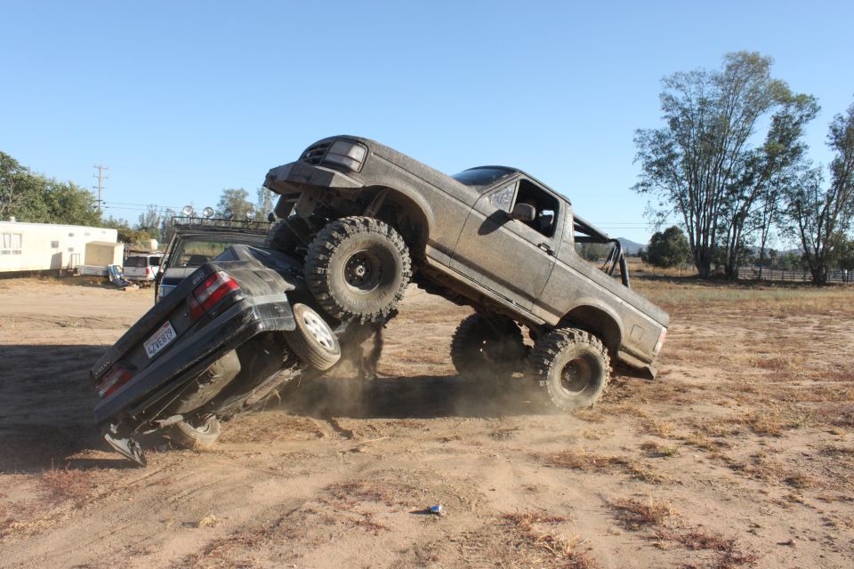 1992 Ford Bronco crushing a sedan in a dirt lot