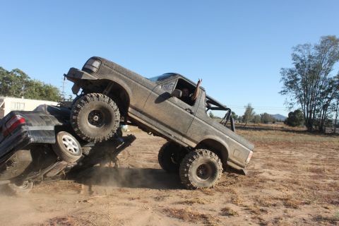 1992 Ford Bronco crushing a car, driver giving peace sign