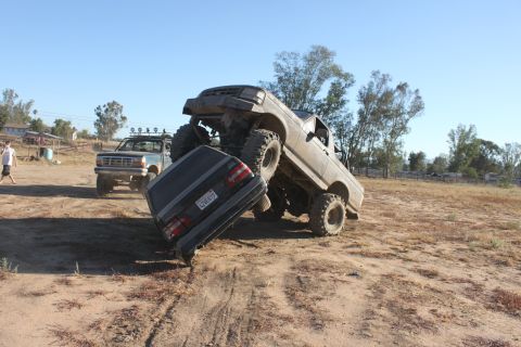 Modified 1992 Ford Bronco on top of a car. Another Ford truck is parked behind
