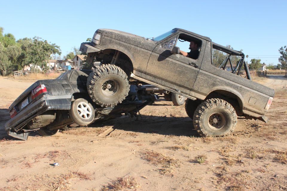 1992 Ford Bronco crushing a sedan on a dirt trail