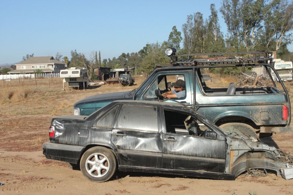 1992 Ford Bronco with roof rack and light, parked next to a wrecked black sedan
