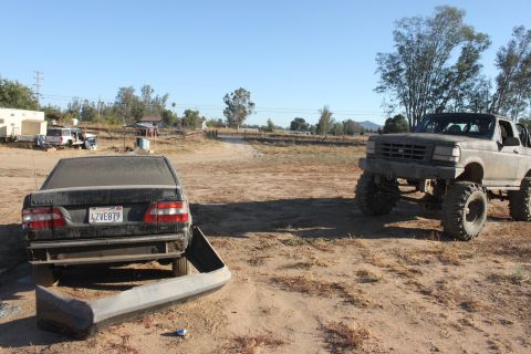 1992 Ford Bronco lifted with large tires, parked next to a damaged sedan