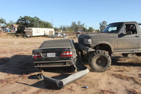 Big lifted truck is crushing the rear of a sedan. Bumper is detached