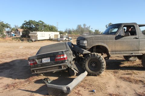 1992 Ford Bronco crushing a black car, front 3/4 view