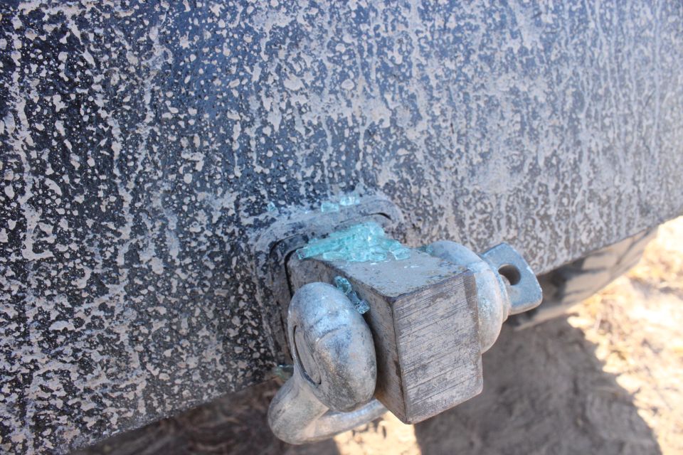 Close-up of a dirty vehicle's tow hitch with broken glass fragments