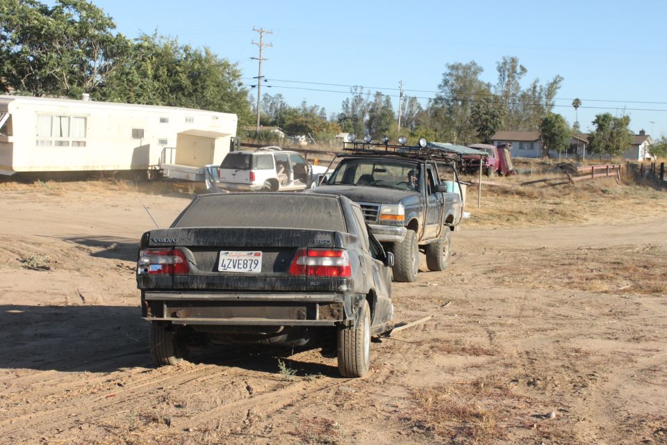 Black sedan with license plate 4ZVE879 being towed by a pickup truck with a roof rack. Trailer and SUV in background