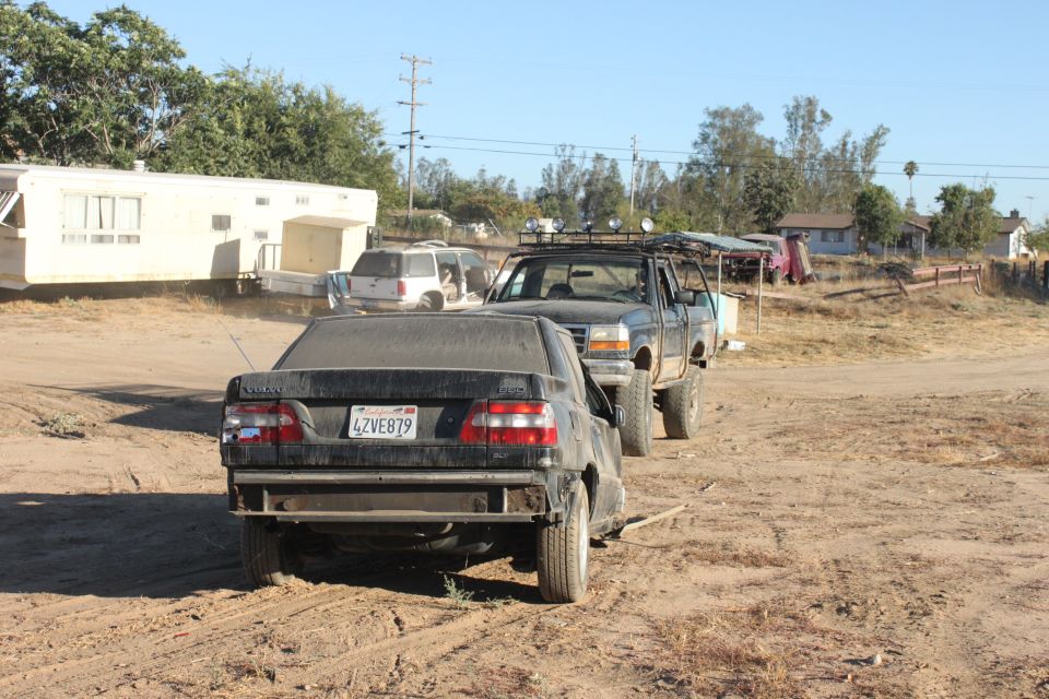 Black sedan with license plate 4ZVE879 being towed by a lifted black pickup truck with a roof rack