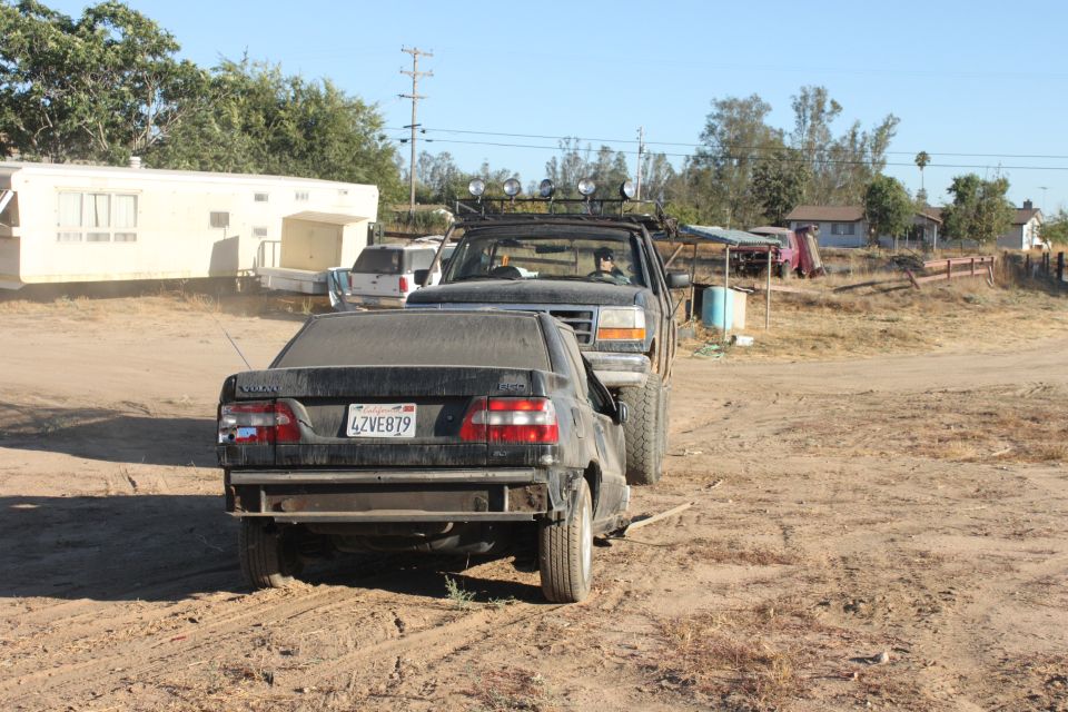 Black sedan's rear end towed by lifted truck; license plate 4ZVE879