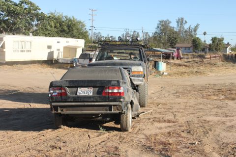 Truck towing a black sedan. Truck has lights on roof. Sedan has license plate 4ZVE879