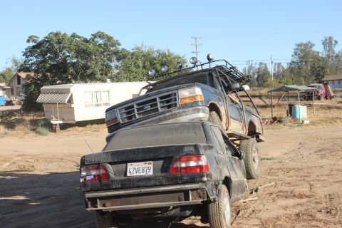 1992 Ford Bronco with roof rack on top of a black Volvo sedan, license plate 4ZVE879