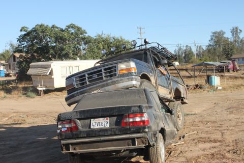 Black 1992 Ford Bronco with a roof rack, perched atop a black Volvo sedan