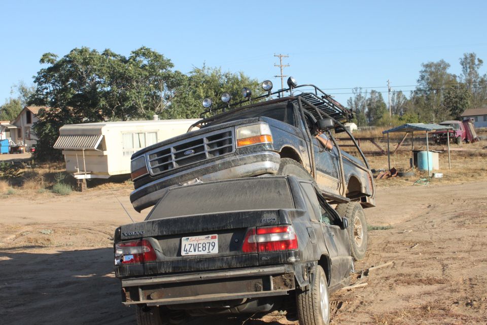 Black 1992 Ford Bronco with a roof rack, perched atop a black Volvo sedan