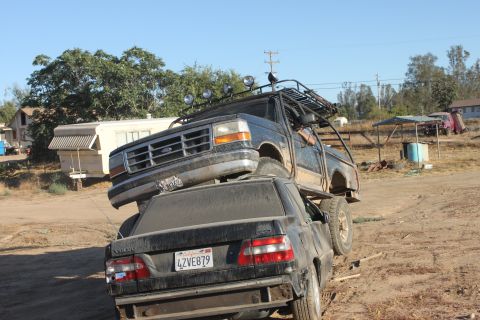 1992 Ford Bronco on top of a black Volvo sedan, front 3/4 view