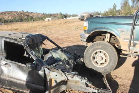 Green Ford Bronco next to a totaled car. Bronco has 'BRONCO' text on fender