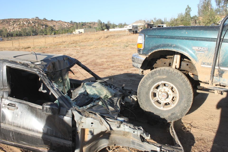 Green Ford Bronco next to a totaled car. Bronco has 'BRONCO' text on fender