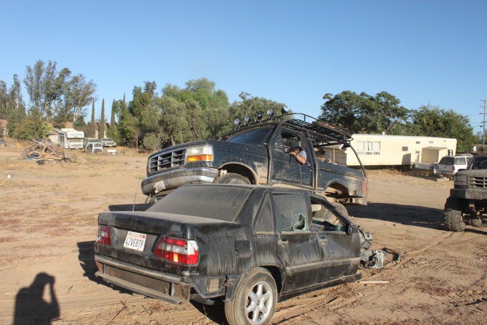 Black 1992 Ford Bronco on top of a black sedan, front view, dusty condition