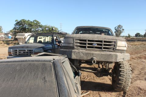 Front view of a lifted 1992-1996 Ford F-Series truck with a custom bumper, parked next to another Ford truck a