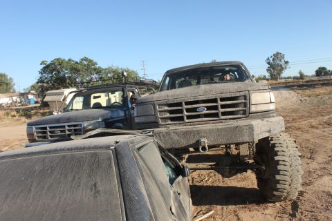 Lifted Ford truck on top of another vehicle, another lifted Ford truck behind it
