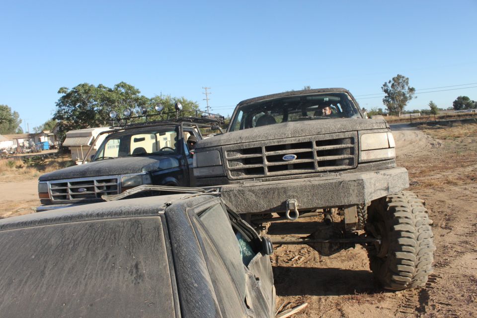 Lifted Ford truck on top of another vehicle, another lifted Ford truck behind it