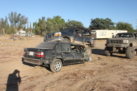 1992 Ford Bronco on top of a black sedan, with another Ford Bronco in the background
