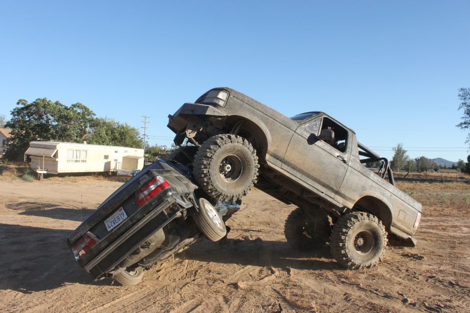 Muddy 1992 Ford Bronco crushing a sedan on a dirt trail