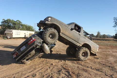 1992 Ford Bronco on top of a crushed car off-road