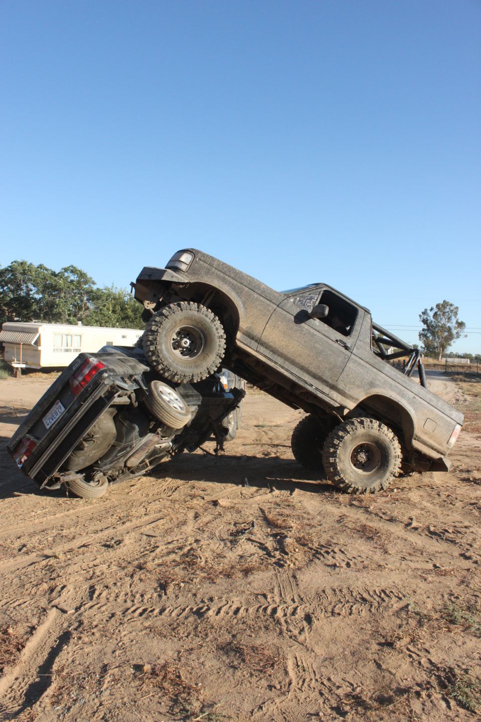1992 Ford Bronco on top of another truck in a dirt lot