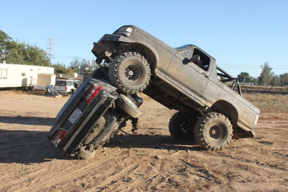 1992 Ford Bronco on top of another truck in a dirt lot
