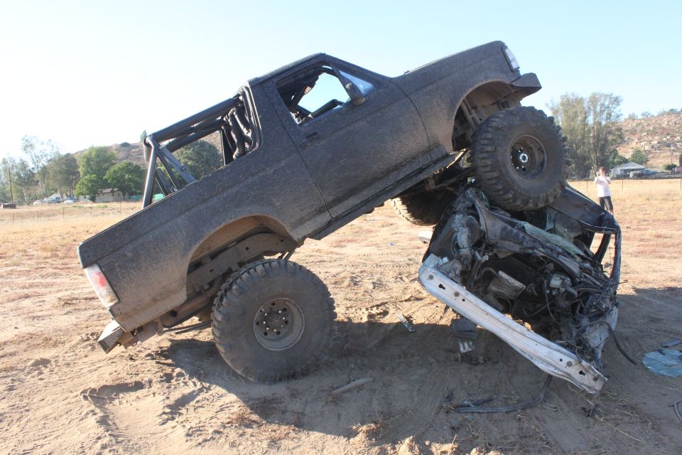 Black 1992 Ford Bronco crushing a car, lifted suspension, off-road tires