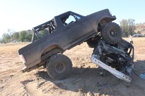 1992 Ford Bronco with roll cage on top of a crushed car