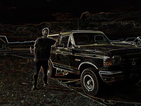 1990 Ford Bronco - A man poses with a 1990 Ford Bronco, captured in a dark, stylized photograph.