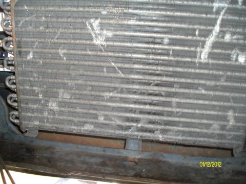 1990 Ford Bronco - The air conditioning condenser shows signs of wear and tear, with debris accumulated on its fins.