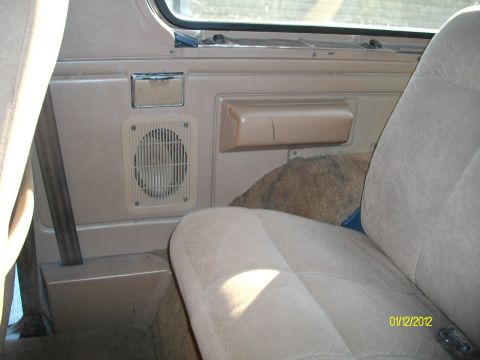 1990 Ford Bronco - Interior shot showing door panel details and rear seat of an older vehicle.