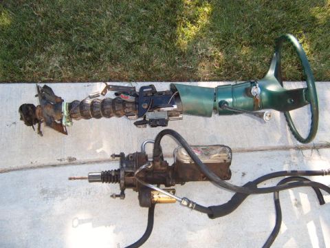 1973 Ford Ranchero - Disassembled steering column and brake master cylinder components laid out on a concrete surface.