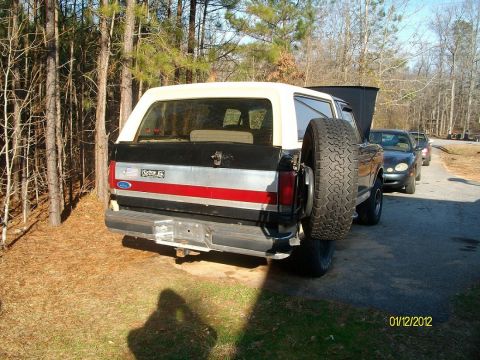 1990 Ford Bronco - Rear view of a 1990 Ford Bronco, a spare tire mounted externally and a distinctive red stripe on its side.