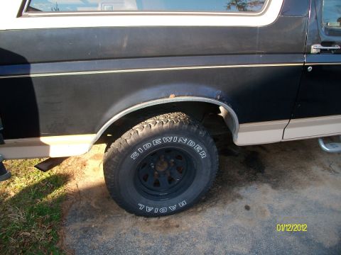 1990 Ford Bronco - Close-up of the rear wheel well and side panel of a 1990 Ford Bronco.