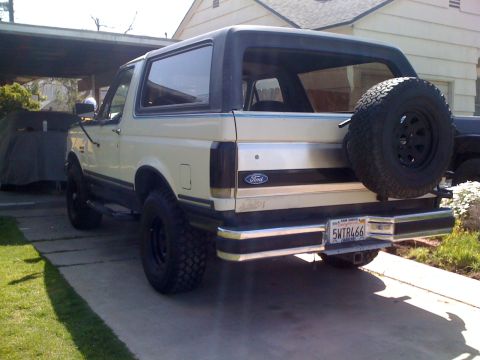 1989 Ford Bronco - This 1989 Ford Bronco is seen from the rear, a cream and black exterior with a spare tire mounted on the tailgate.