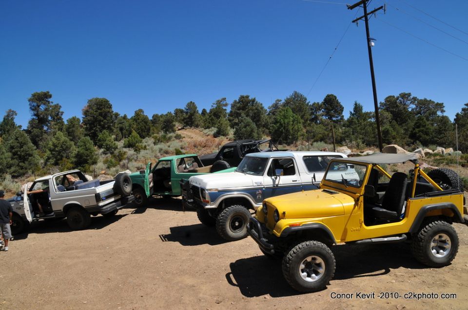 Yellow Jeep Wrangler and white Ford Bronco parked with other trucks