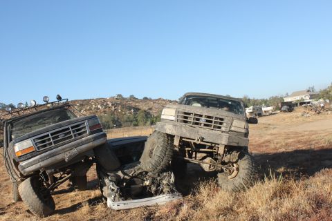 1992 Ford Bronco stuck in dirt next to another truck