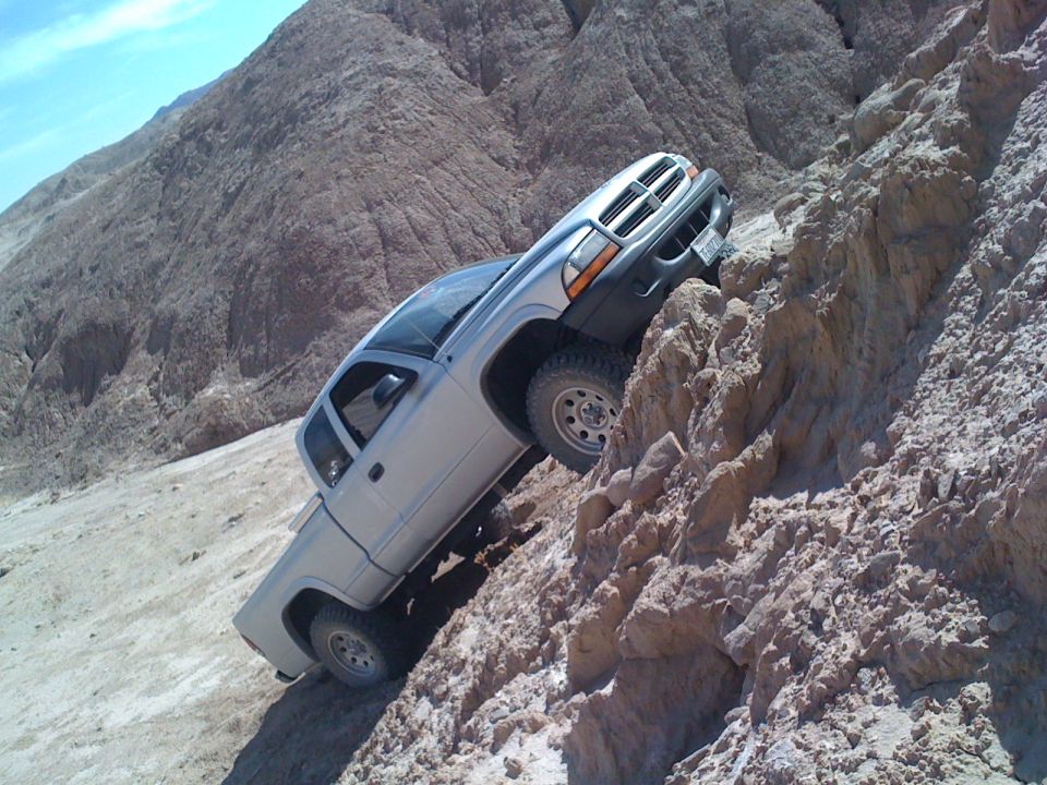 Silver Dodge Dakota pickup truck climbing a steep, rocky hill