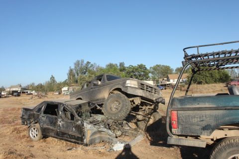 Mud-covered 1992 Ford Bronco on top of a crushed black sedan, front view
