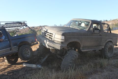 Mud-covered 1992 Ford Bronco stuck in dirt, front grille visible